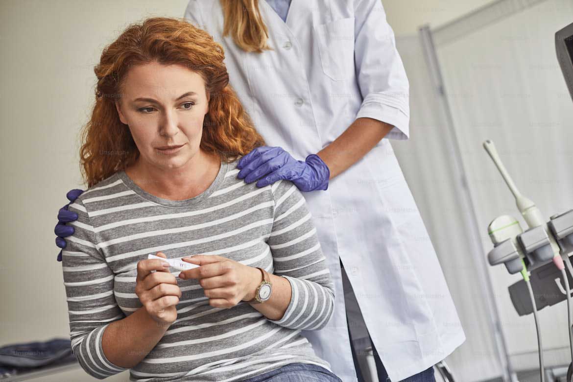 An unhappy woman holding a negative pregnancy strip